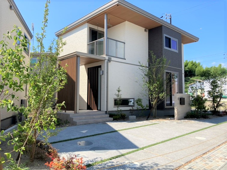 「緑に誘われるやすらぎの住まい」 ― オークの床がもたらす落ち着いた風合いが心地よく調和した住まい。玄関脇の地窓から見える低木の枝葉が、訪れる人をそっと迎えます。リビング脇の余白は、庭とつながるもう一つのくつろぎの場に。
